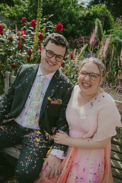 bride and groom in garden confetti or flowers being thrown over them they smile and laugh