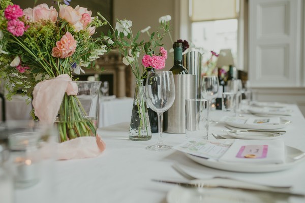 empty dining room setting with cutlery red wine in buckets glasses and flowers on table