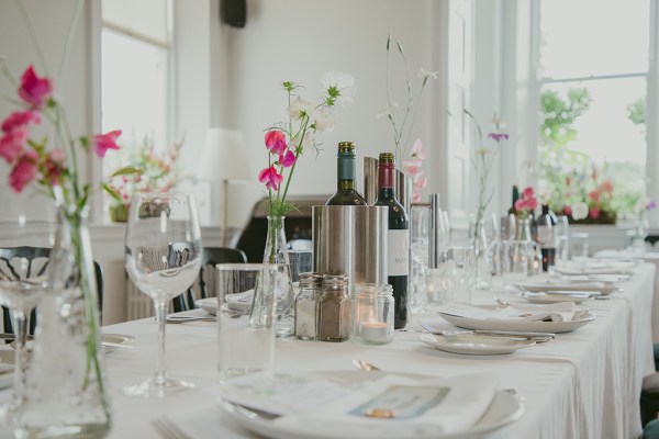 empty dining room setting with cutlery red wine in buckets glasses and flowers on table