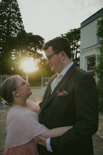 sunshine sunset through couple behind them as they face each other in garden