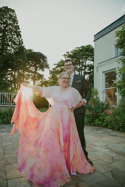 sunshine sunset through couple behind them as they face each other in garden they dance