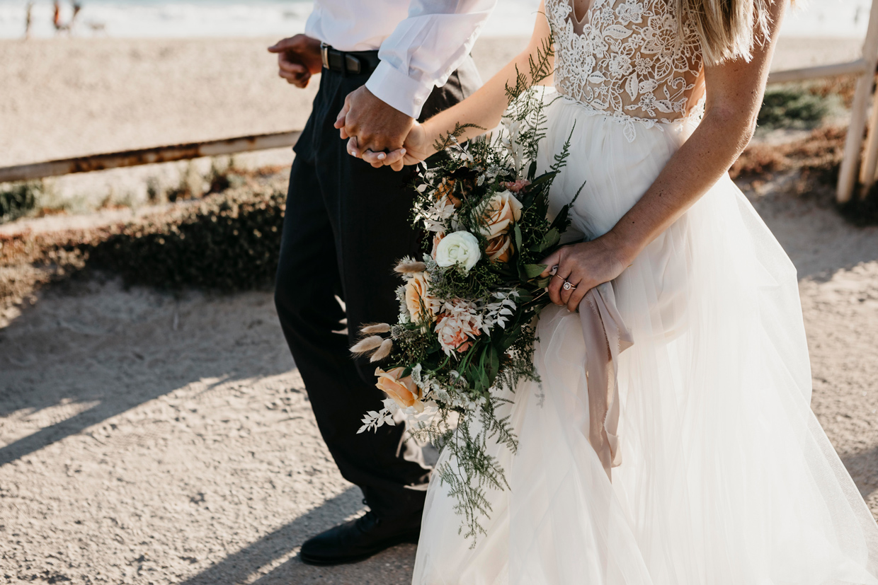 newlywed couple walking hand in hand