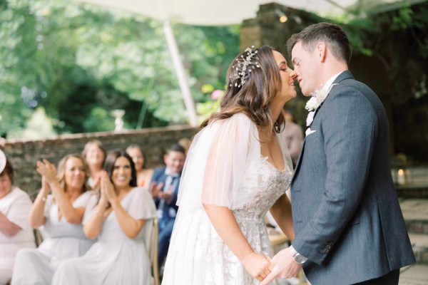 bride and groom going in for a kiss during ceremony guests clapping