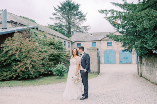 bride and groom stand in the courtyard together they begin to walk