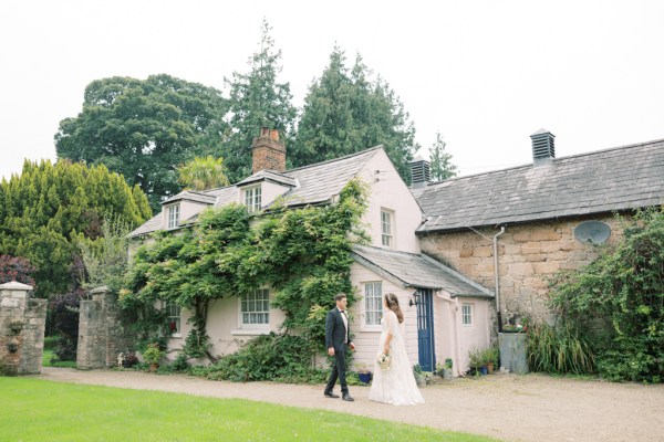 bride and groom walk along the courtyard to wedding venue house