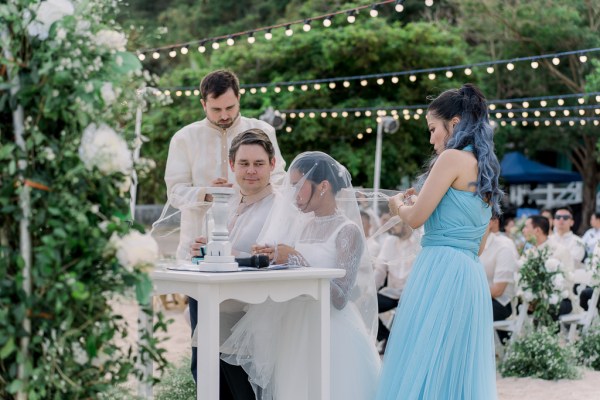 veil covers brides face as she signs marriage certificate