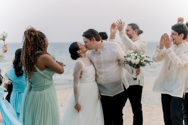 bride and groom kiss on the sand