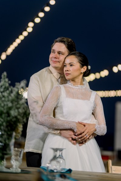 groom hugs bride from behind they smile