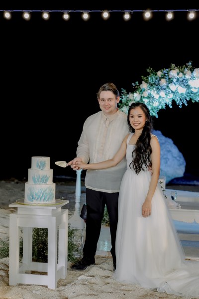 bride and groom cutting the white and blue wedding cake