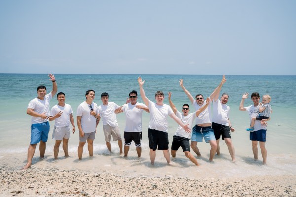 groom and his groomsmen playful on the sandy beach ocean sea in background