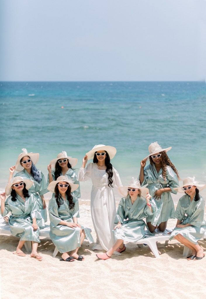 bride and bridesmaids wearing sun hats and sunglasses ocean sea view in background