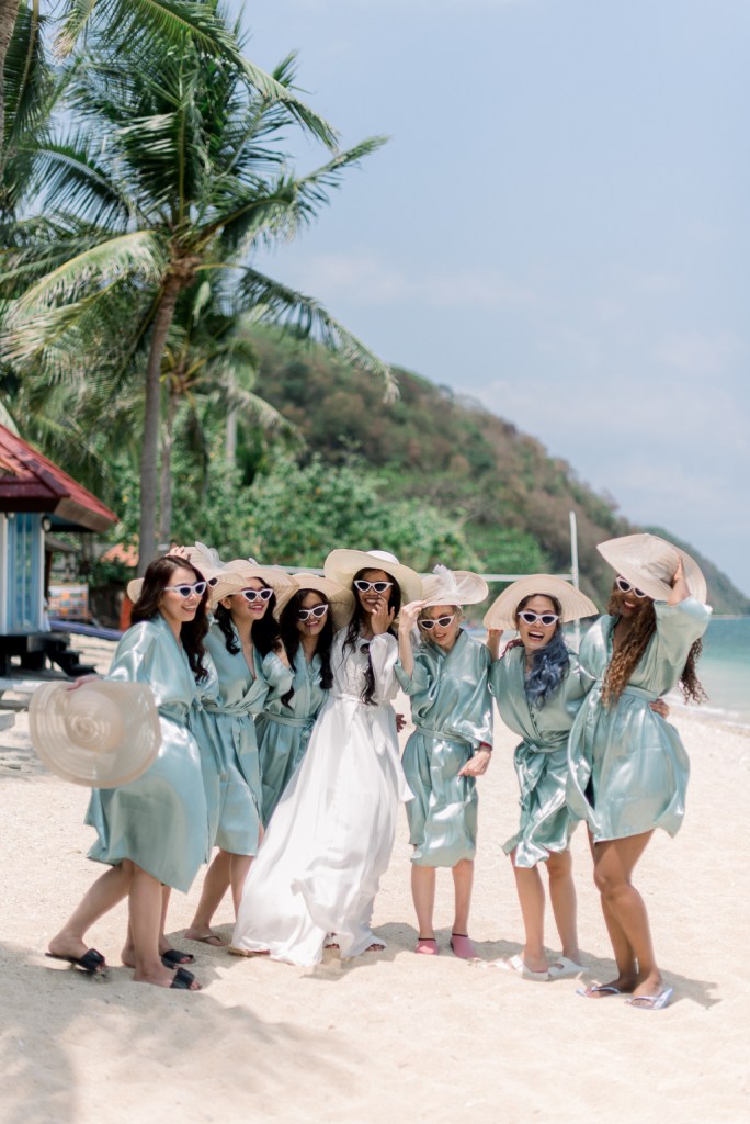 bride and bridesmaids wearing sun hats and sunglasses ocean sea view in background