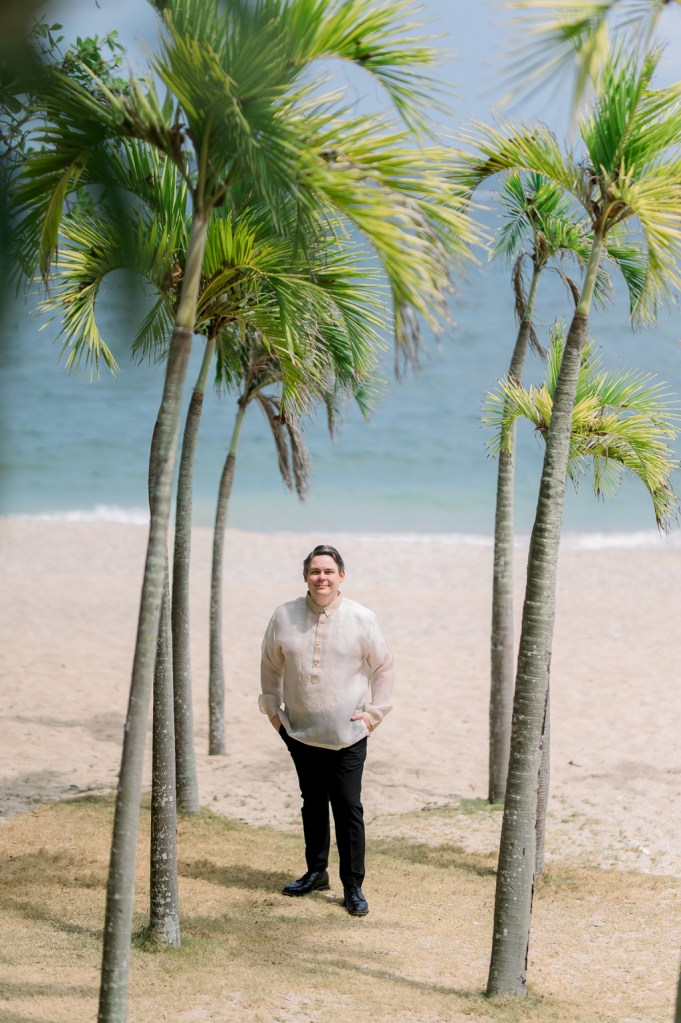 palm trees ocean sea in background and groom in the middle