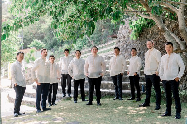 groom and groomsmen pose in front of steps together