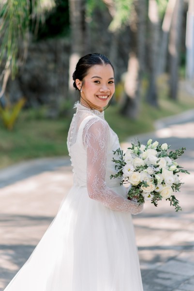 bride on her own poses on pathway holding bouquet