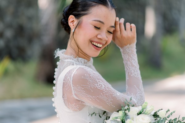 Bride holding white bouquet flowers in hand looks down