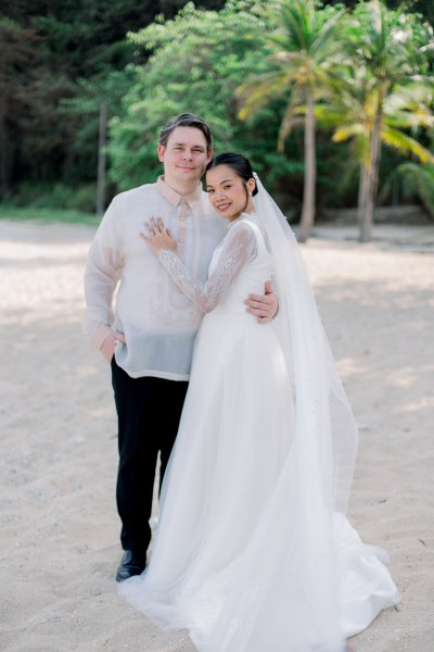 bride places hand on grooms chest as they stand on the sand