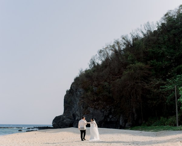 wide shot view of sand and bride and groom walking