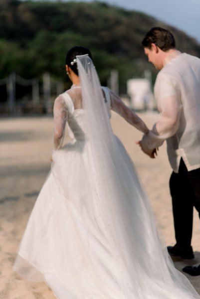 bride from behind veil groom holds her hand