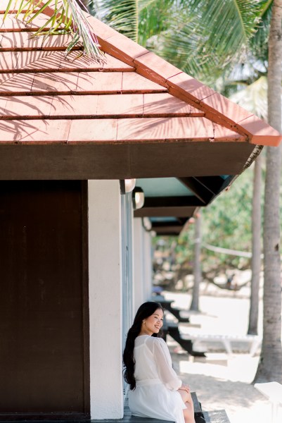 bride sitting in the sunshine under hut