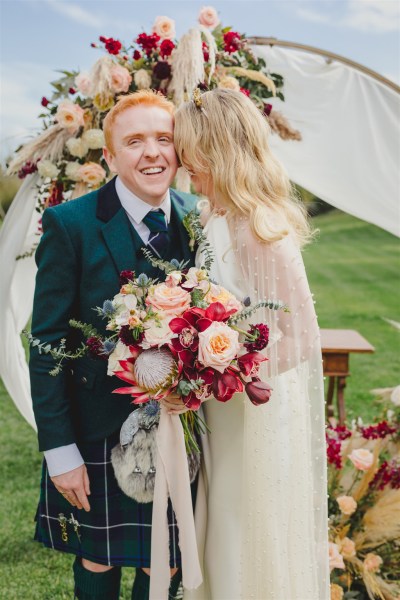 bride and groom smile she holds bouquet