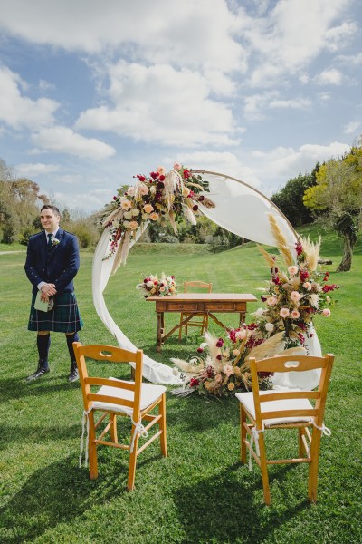 groom stands awaiting his bride at the flower bed alter