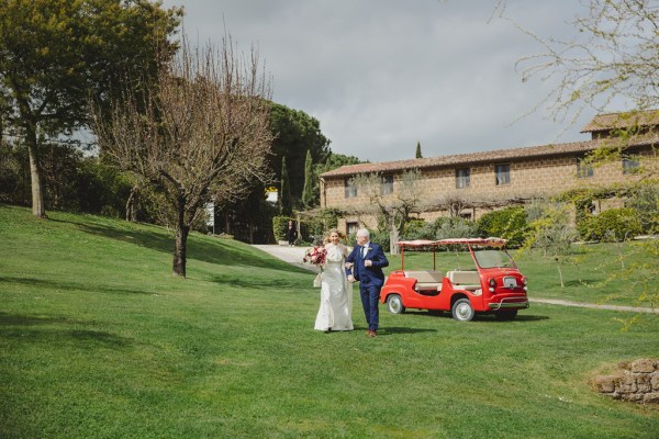 father of the bride gets out of wedding caddy with daughter and walks her towards ceremony