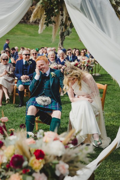 bride and groom laughing a lot at alter to ceremony guests behind them