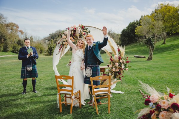 bride and groom in front of circular flower bed at alter to wedding