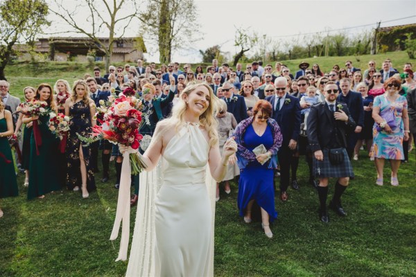 bride smiles in front of guests behind her walking