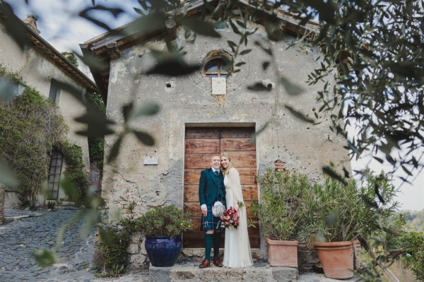 bride and groom pose in front of old abandoned house warehouse