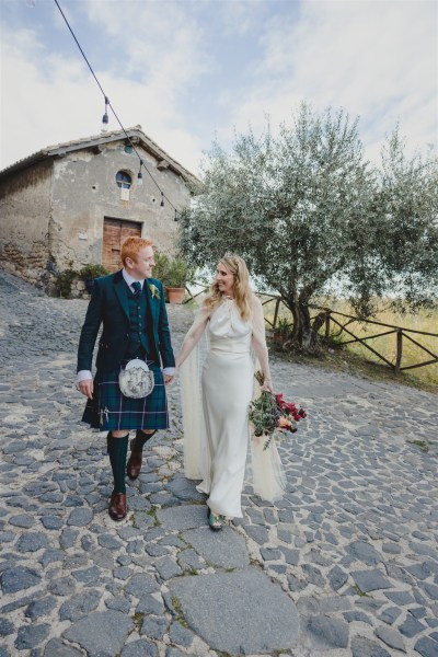 bride and groom walk in courtyard hand in hand