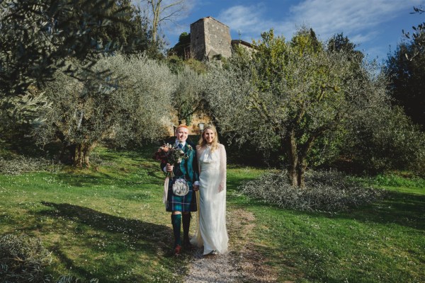 groom and bride pose together in farm grass setting