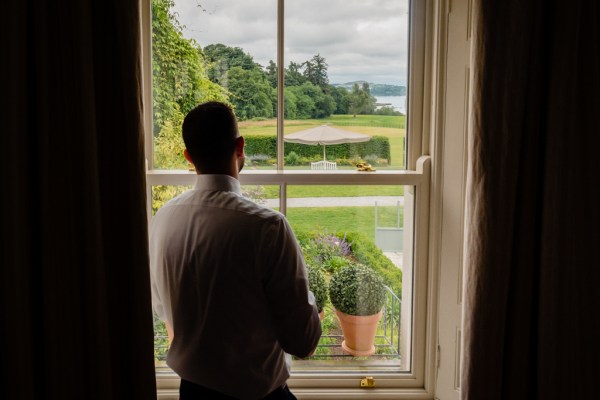 groom looks out towards garden through window