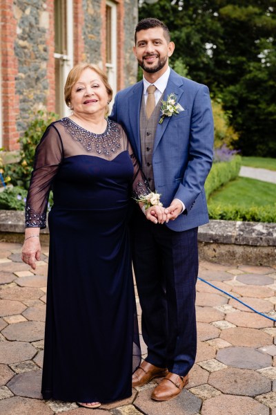 mother and son groom holding hands in courtyard