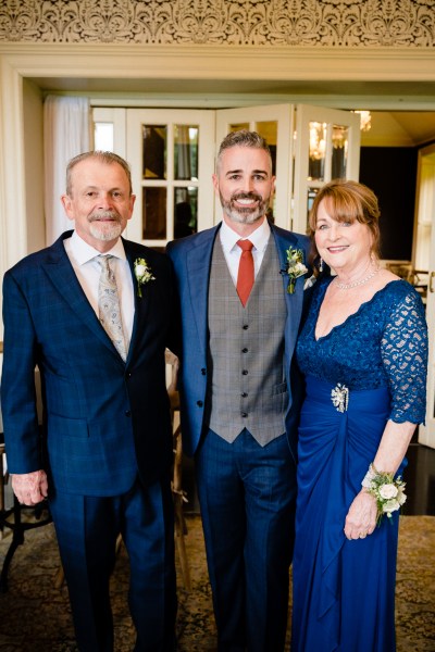 groom mother and father pose for a photo