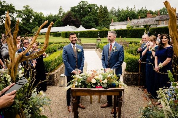 grooms stand at top of alter setting in front f guests