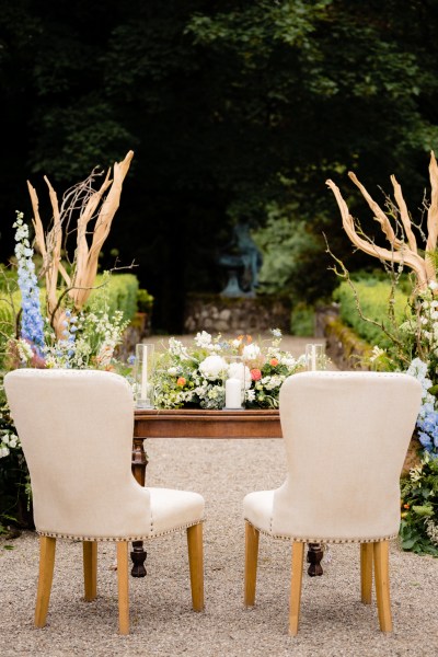 alter table wooden covered in flowers and candles two chairs for the grooms