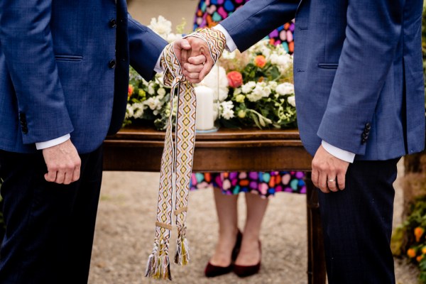 grooms are bound by ribbon celebrant in background