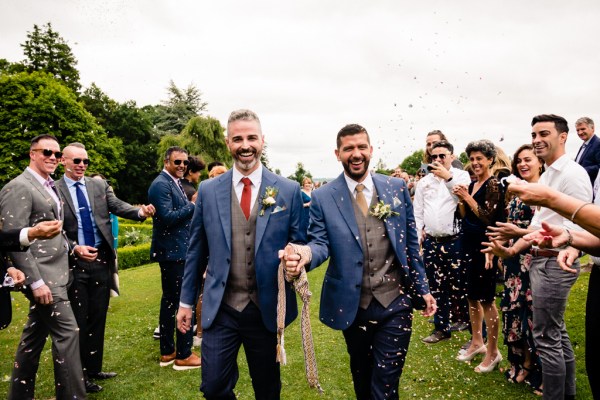 guests clap for the happy grooms as they smile