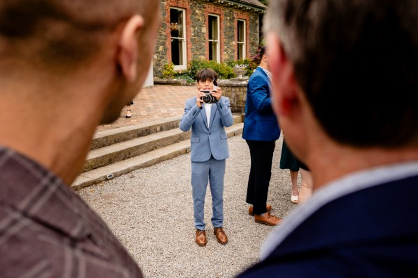 man in blue suit takes polaroid picture of couple