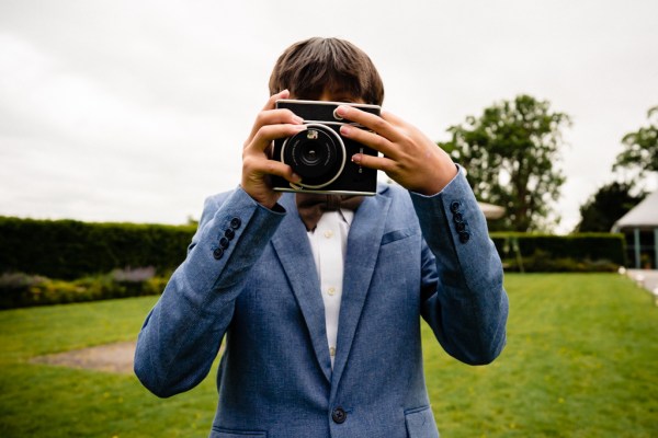 man in blue suit takes polaroid picture