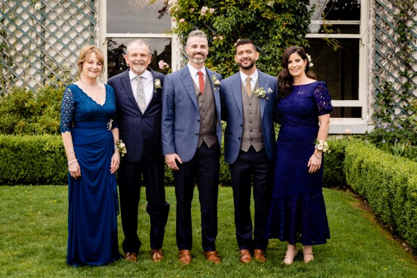 grooms mother father family pose for photo on grass