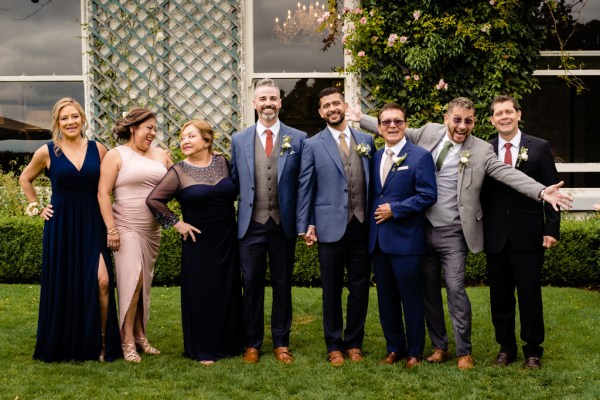 grooms mother father family pose for photo on grass