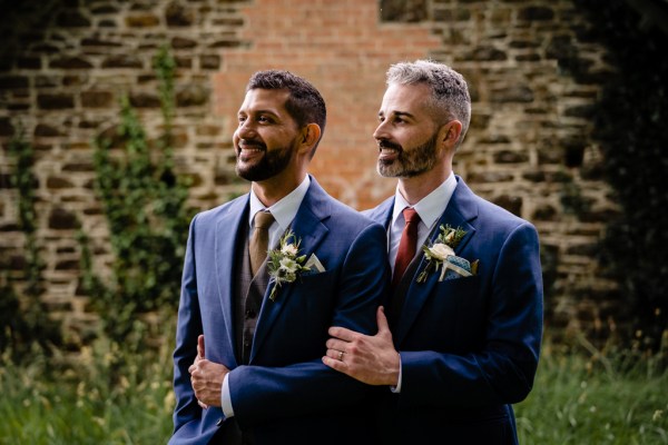 grooms stand together holding each other