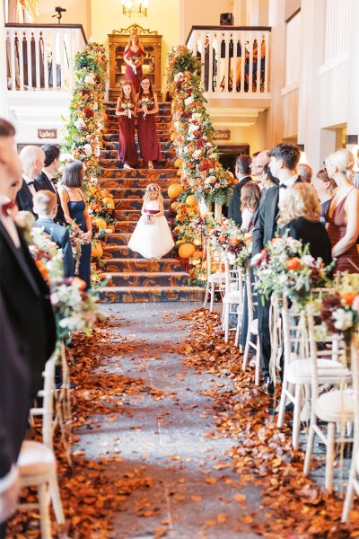 Little flower girl walks down the stairs towards the aisle