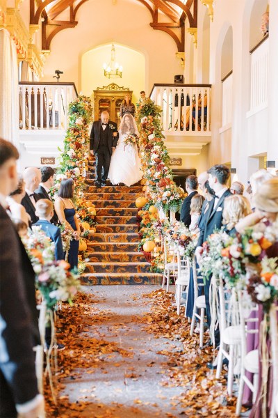 Father of the bride walks his daughter down the aisle she covers her face with veil guests watch