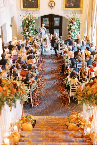 Pumpkins autumnal theme orange flowers laid out on stairs view of ceremony