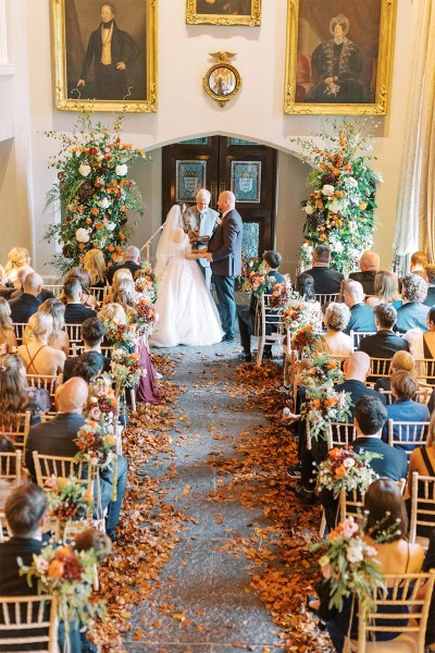 Bride and groom at top of alter setting portraits hanging on wall guests seated they are with the celebrant