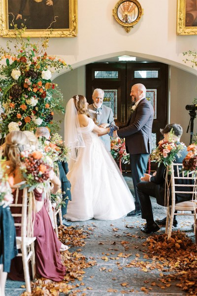 Bride and groom laugh together at the top of the alter in front of guests